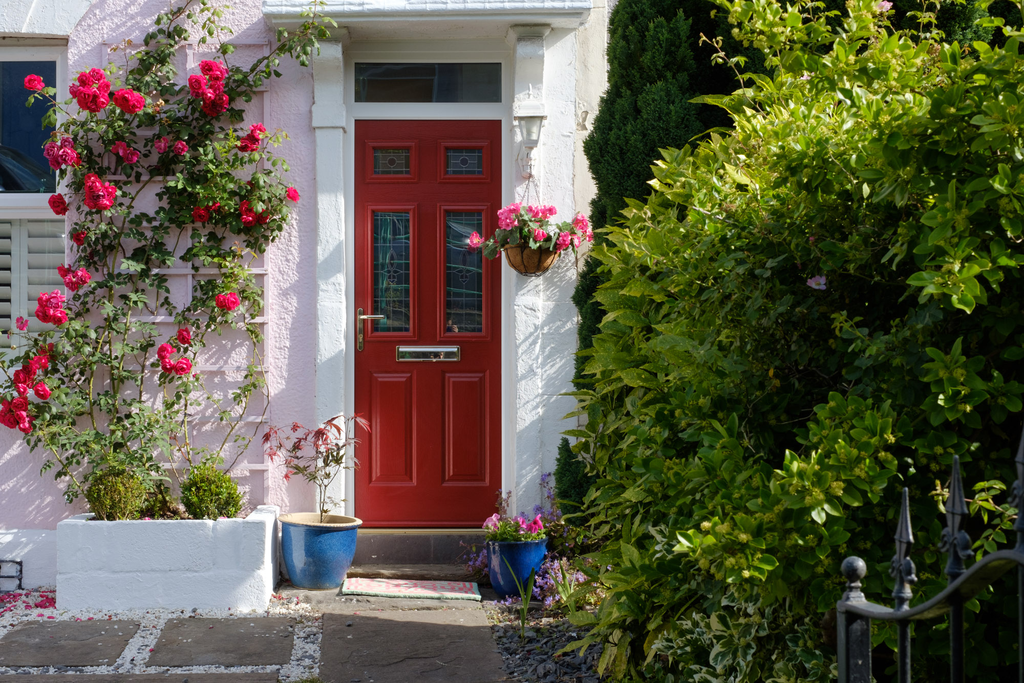 Red traditional composite door with decorative leaded glass on a whitewashed cottage